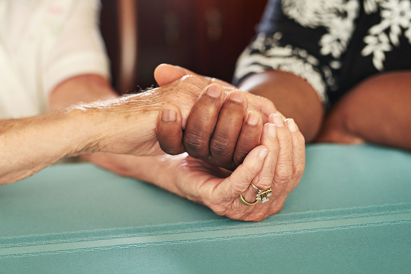 Two elderly women holding each others' hands in solidarity and comfort
