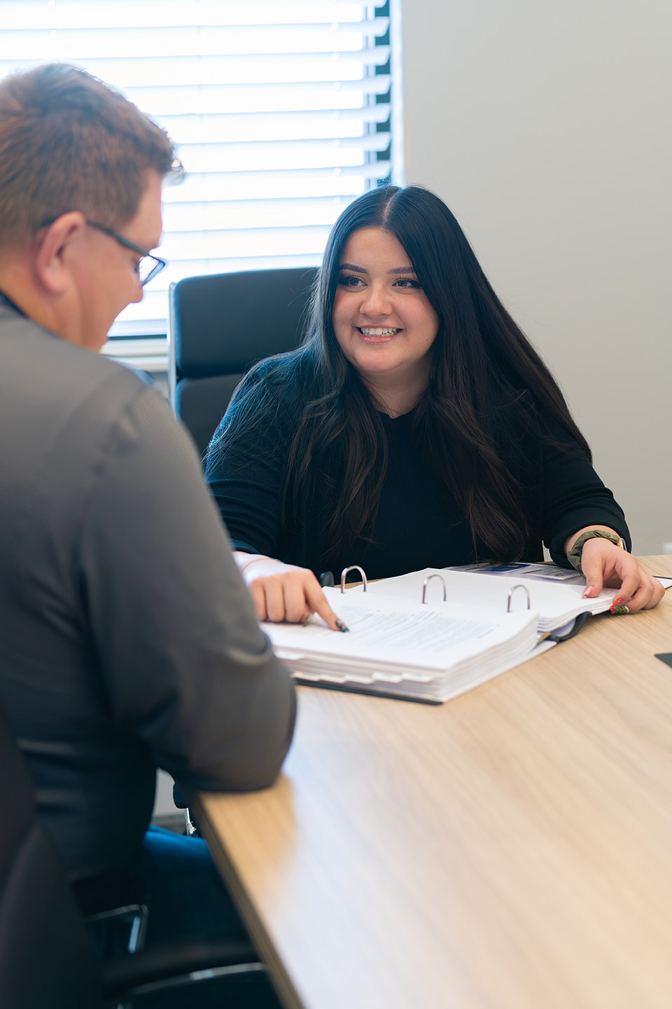 Woman smiling graciously as she assist her client with his estate planning